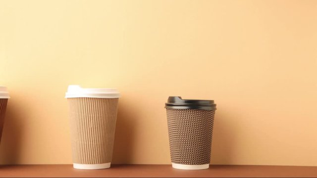A lot of disposable cups for coffee and tea change places. Nice catering for a coffee shop. Video footage stop motion timelapse. Beige background.