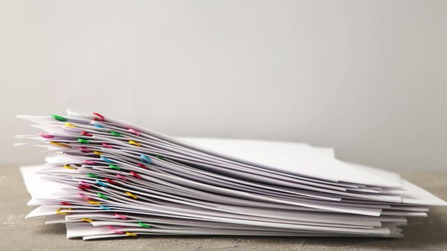 Stack overload document report paper with colorful paperclip on grey background, business concept footage paperless used &ndash; 4K Stop motion.