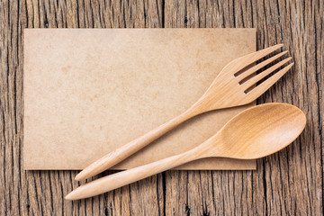 Teak wooden fork and spoon on blank old brown cardboard paper on space of old wood background