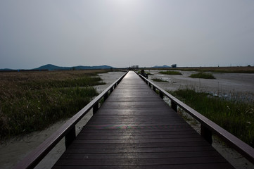 Obraz premium wooden seaside bridge through the seashore.on the sunset time.