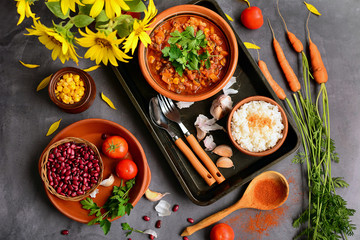 Top view of a table with dishes with beans, corn, tomatoes, parsley, garlic. Kitchen still life with sunflowers.