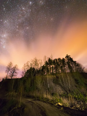 Starry skies with light beams over a hill