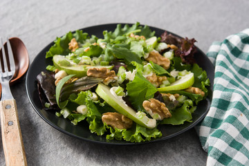 Fresh Waldorf salad with lettuce, green apples, walnuts and celery on gray stone