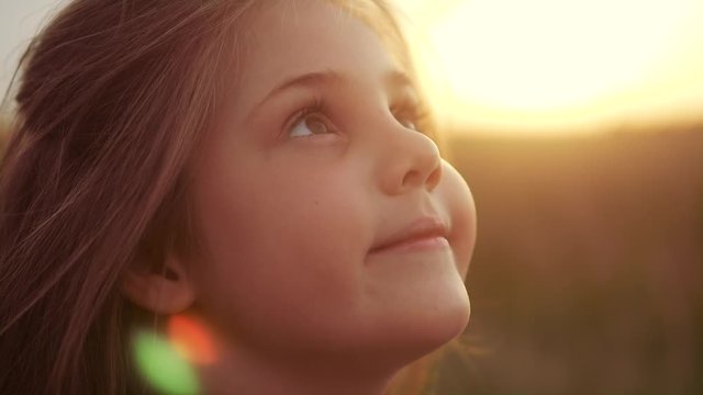 happy little girl child closed her eyes dreams. kid wants a dream come true portrait at sunset. baby daughter silhouette dreaming of a happy childhood. free face sister lifestyle side view thinks