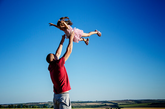 Strong paternal arms. Happy child with a small child are playing. Summer and children. A happy family. The child happily plays with his father. Dad and daughter close up.