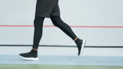 Fototapeta na wymiar Male jogger training at stadium track. Athlete legs running on racetrack