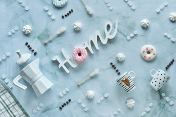 Creative wintertime flat lay on light mint blue stone background. Ceramic coffee cups, coffee maker, sugar and sugar sticks. Sweets, doughnuts and marshmallows.