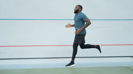 Fototapeta na wymiar African american man jogging on stadium. Runner doing cardio workout outdoors