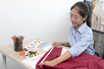 Asian clothing designers are measuring sample sizes to prepare evening gowns for important customer orders.