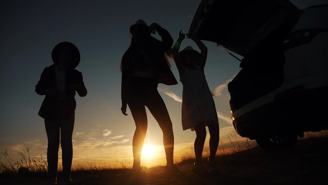happy family kid dance picnic are little girl jumping dancing dream holiday concept. group of children happy family jump three girls teenagers are standing at sunset next to the car stopped at a