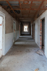 Fototapeta na wymiar Corridor of a destroyed old hotel with broken doors and damaged floor