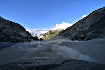 Glacier river in the alps in valais in switzerland with a bright blue sky