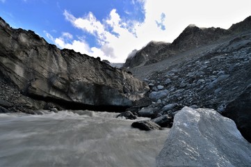 Glacier river from a glacier cave in the alps in valais in switzerland with a bright blue sky