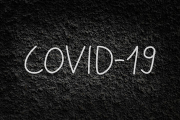 COVID-19; coronavirus disease written on black rough wall texture