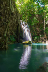 Fototapeta premium Clear stream that flows through the rocks. Falling into the Emerald Pool, Erawan Kanchanaburi, Thailand.