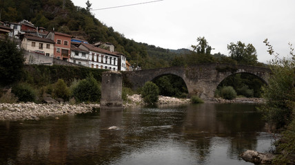 Big bridge with a town with houses and a river with stones