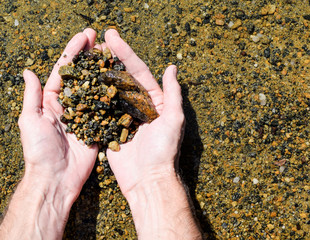Natural sea stones in the hands. Man is holding stones.