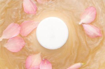 Mockup of cosmetic products. White round jar on water with shimmer and flower petals