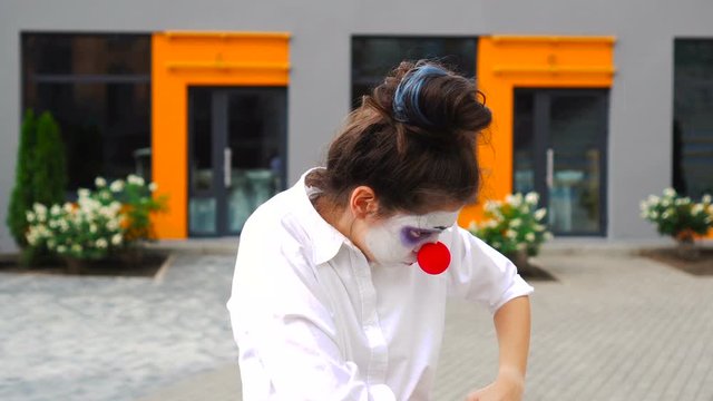 Mim girl or young clown looking directly at the camera looking for a loss outdoor