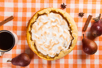 Pear pie with cream, homemade pastries on the table with a orange napkin, coffee and spices. Copy space.
