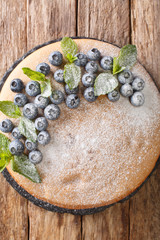 Sponge cake sandwich with blueberries and tender cream close-up on a slate board on the table. Vertical top view from above