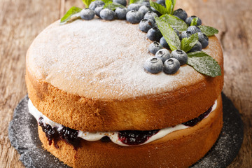 Delicious light sponge cake sandwich with blueberries and tender cream close-up on a slate board on the table. horizontal