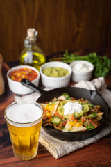 nacho in skillet pan with a glass of beer