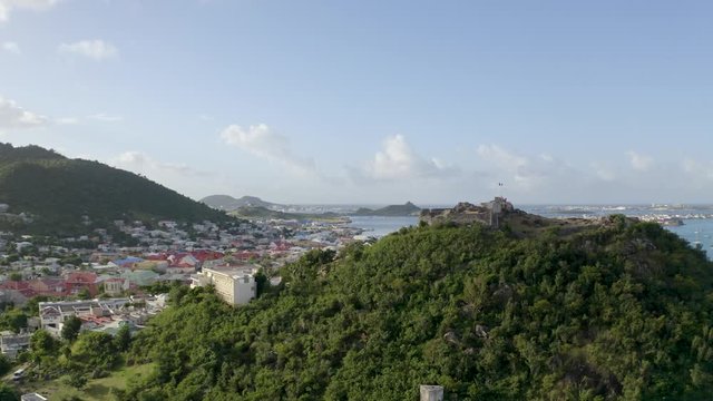 Aerial drone shot rising above Fort St. Louis in Marigot, Saint Martin in the Caribbean with the town, harbour and mountains in the background.