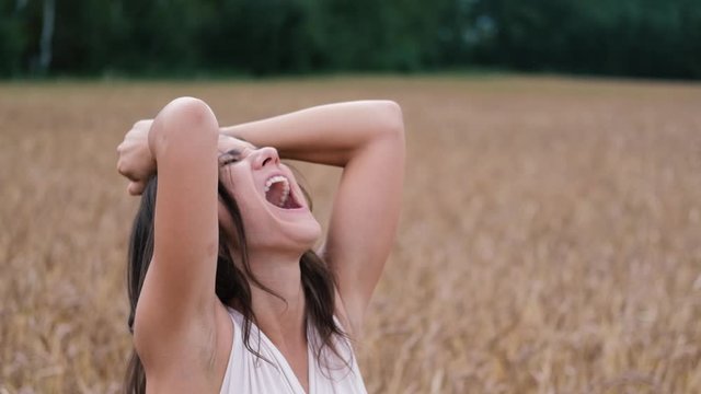 Close-up of a crazy angry young woman in a field screaming loudly with all her might, angry, expresses rage, anger and aggression.