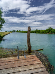 Lagoon landscape with wild nature, wooden jetty and blue sky