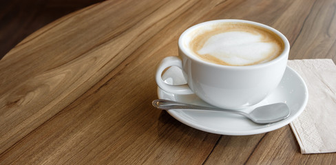 closed-up of hot drink coffee in white mug on brown wood table with small spoon