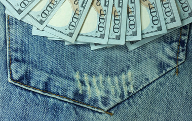 A fan of dollar bills on the pocket of denim pants. Close-up        