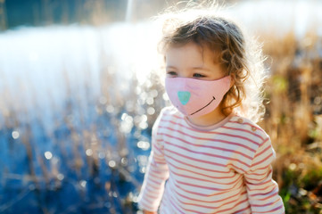 Naklejka premium Small girl with face mask outdoors in nature, walking.
