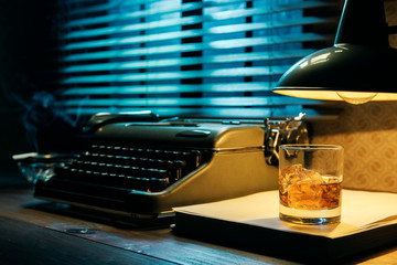 Vintage writer desktop with typewriter and a glass of whiskey