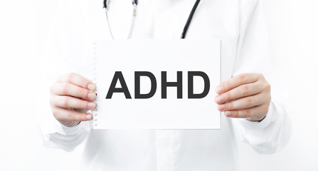 Doctor holding a card with text ADHD, medical concept.