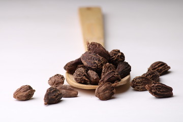 Indian spice - Black cardamom whole seeds in a spoon on white background