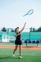Young girl playing with racket, throwing it up in the air and flipping