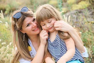 Joyful mom and daughter sit in the open air