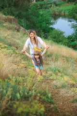 Mom and daughter walk by the hand along the path on the rocky slope
