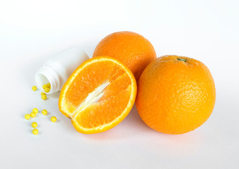 Fresh oranges on a white plate, one sliced. Yellow vitamins in a white jar on a white isolated background. View from above. Vitamins, health, beauty. Healthy lifestyle concept.
