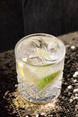 Cocktail drink on a old stone board. Alcoholic beverage with tropical fruits red pepper herb and ice. cocktail in glass on black background. Copyspace. Close up of glass of cocktail 