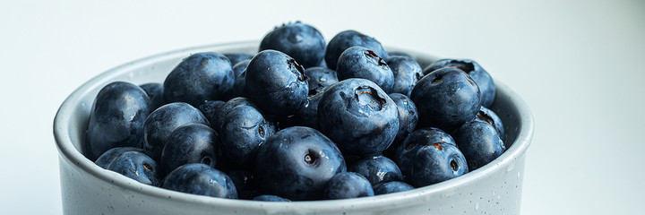Blueberries in a gray pot on a light gray table. Close-up pot