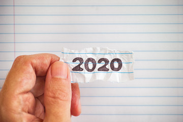 Person holding a peice of paper with the year 2020 on it