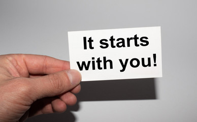 Message on the card IT STRATS WITH YOU, in hands of businessman.