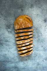 Loaf of sliced sourdough bread on a dark background, top view, food top down. Handmade Whole Grain Dark Bread