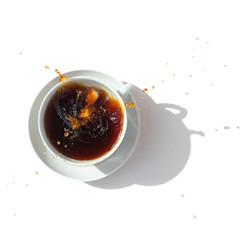 Black coffee in a white cup, top view. Sugar lumps are thrown into the cup, spectacular splashes are spilling out of the cup. White background. International coffee day.