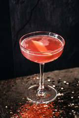 Cocktail drink on a old stone board. Alcoholic beverage with tropical fruits red pepper herb and ice. cocktail in glass on black background. Copyspace. Close up of glass of cocktail 