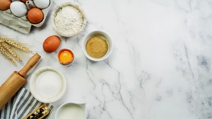 Ingredients for baking - Flour,sugar,eggs,milk, rolling pin on white marble background with copy space