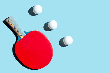 Red racket for table tennis with white balls on blue background. Ping pong sports equipment in...