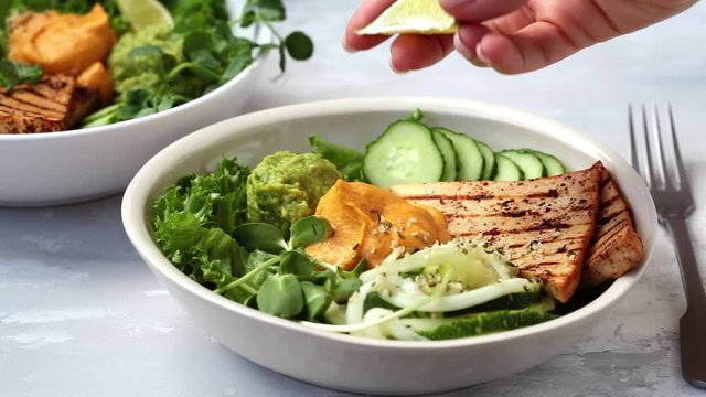 Vegan lunch - buddha bowl with zucchini pasta, grilled tofu, guacamole, sweet potato hummus and vegetables, gray background.